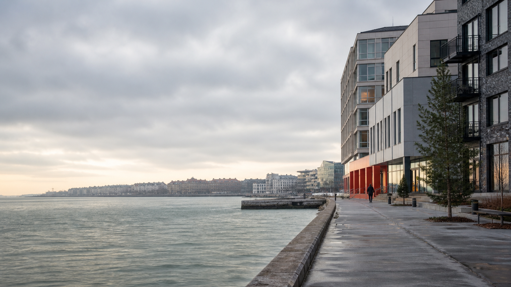 A quiet waterfront promenade beside contemporary northern architecture